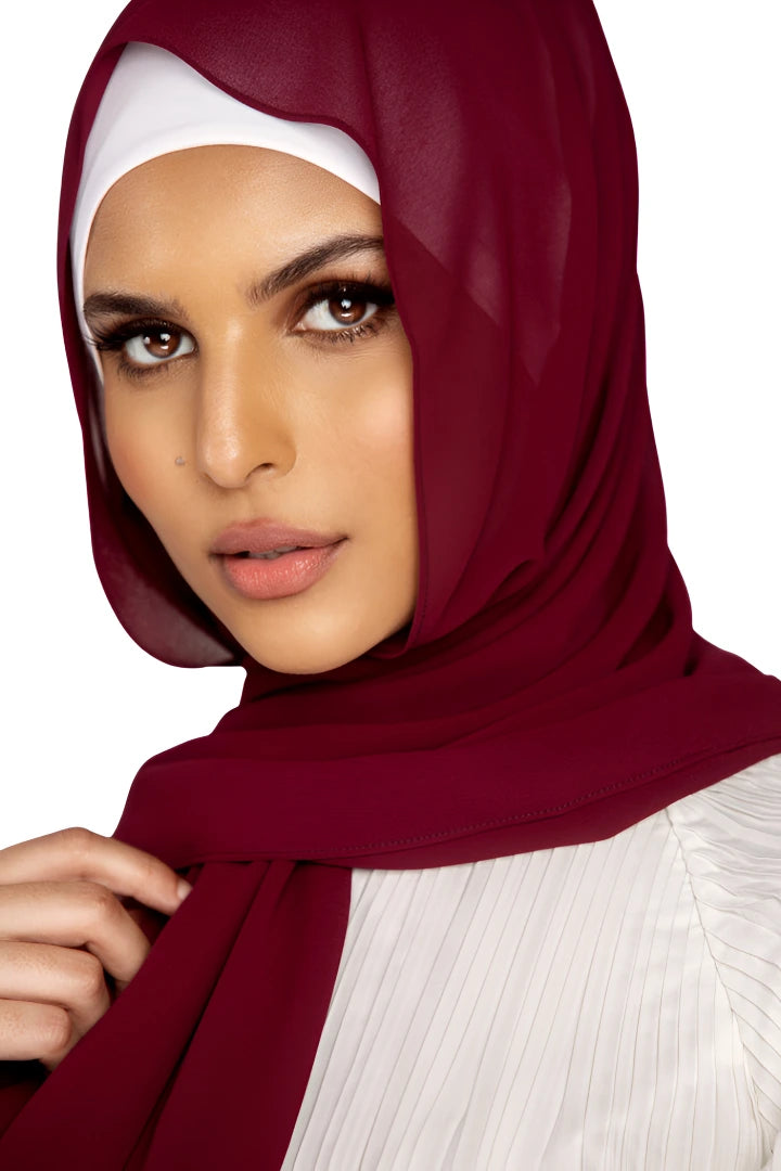 Woman wearing a burgundy hijab with a white background