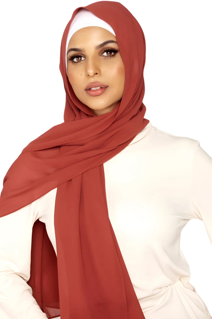 Woman wearing a red hijab and white top on a white background