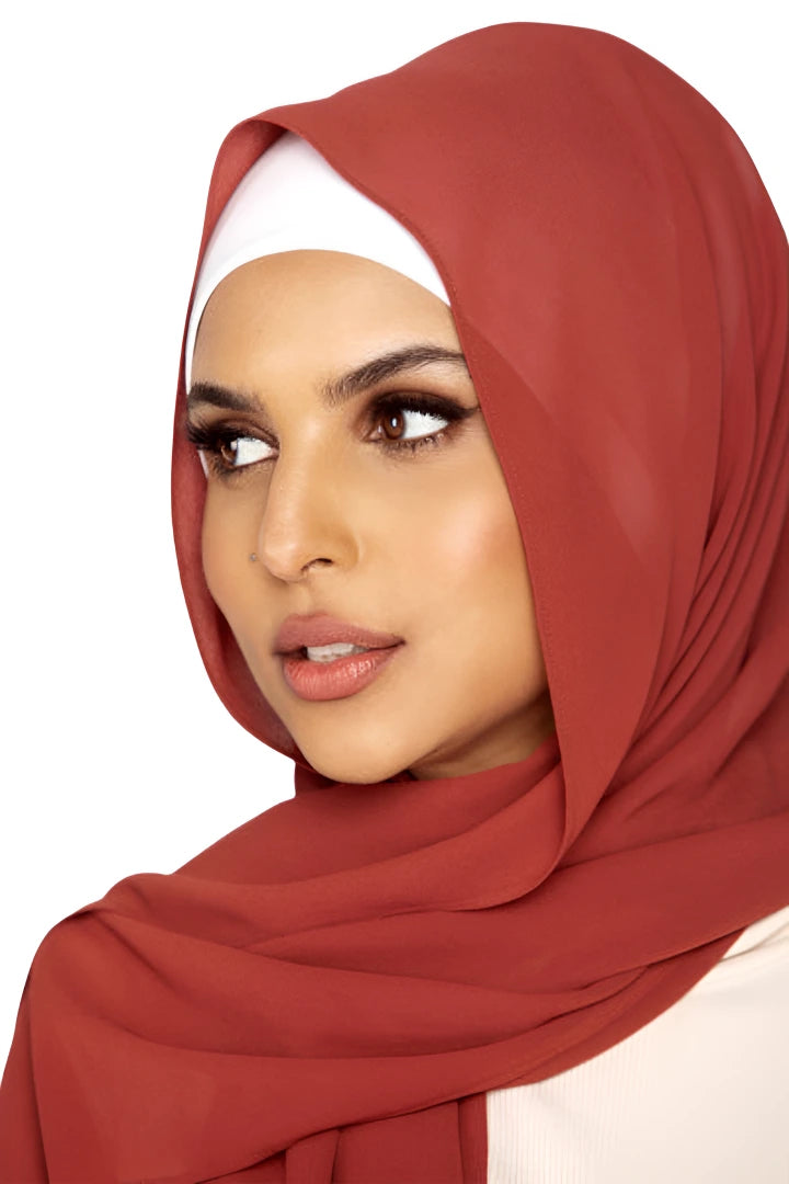 Woman wearing a red hijab and white top on a white background