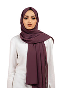 Woman wearing a dark purple hijab on a white background
