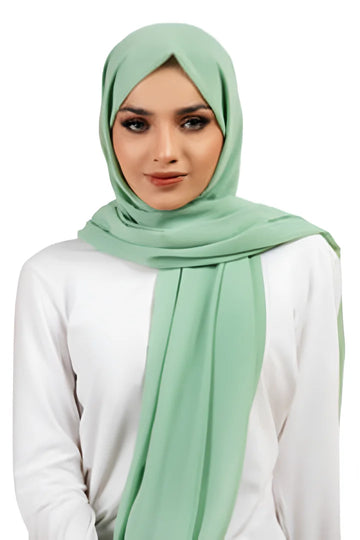 Woman wearing a light green hijab and white top on a white background