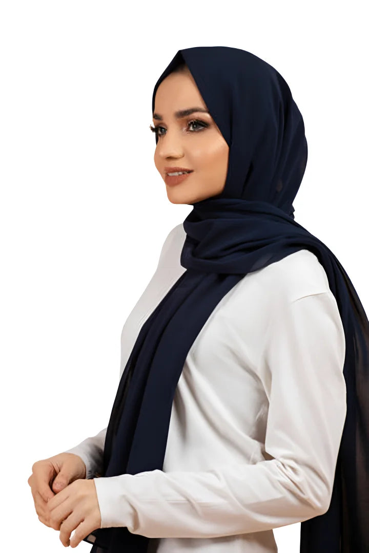 Woman wearing a navy hijab and white top on a white background