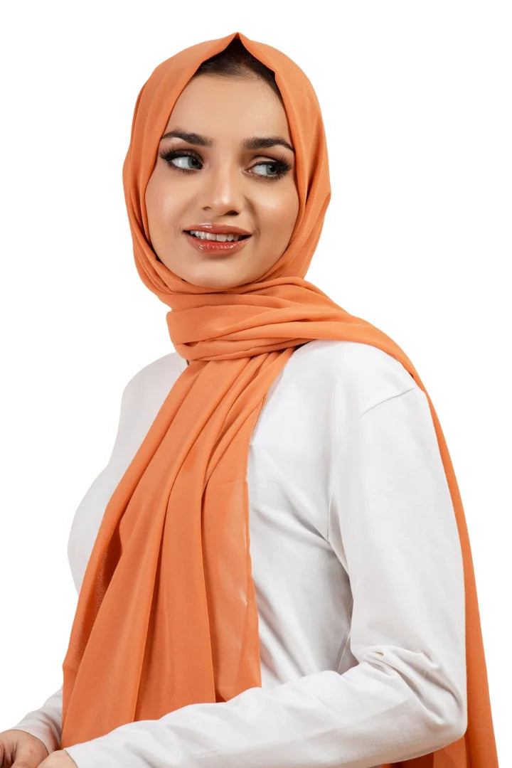 Woman wearing an orange hijab and white top on a white background