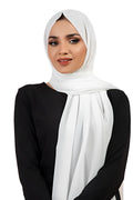 Woman wearing a white hijab and black top on a white background