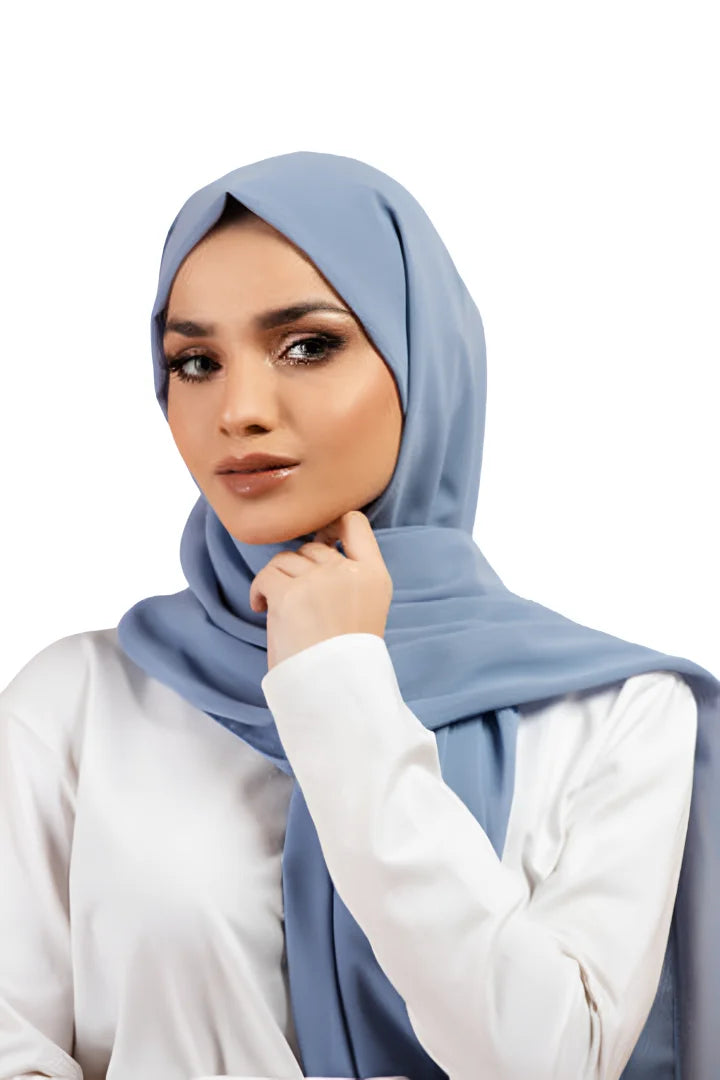 Woman wearing a light blue hijab and white shirt on a white background