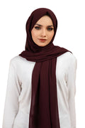 Woman wearing a dark red hijab on a white background