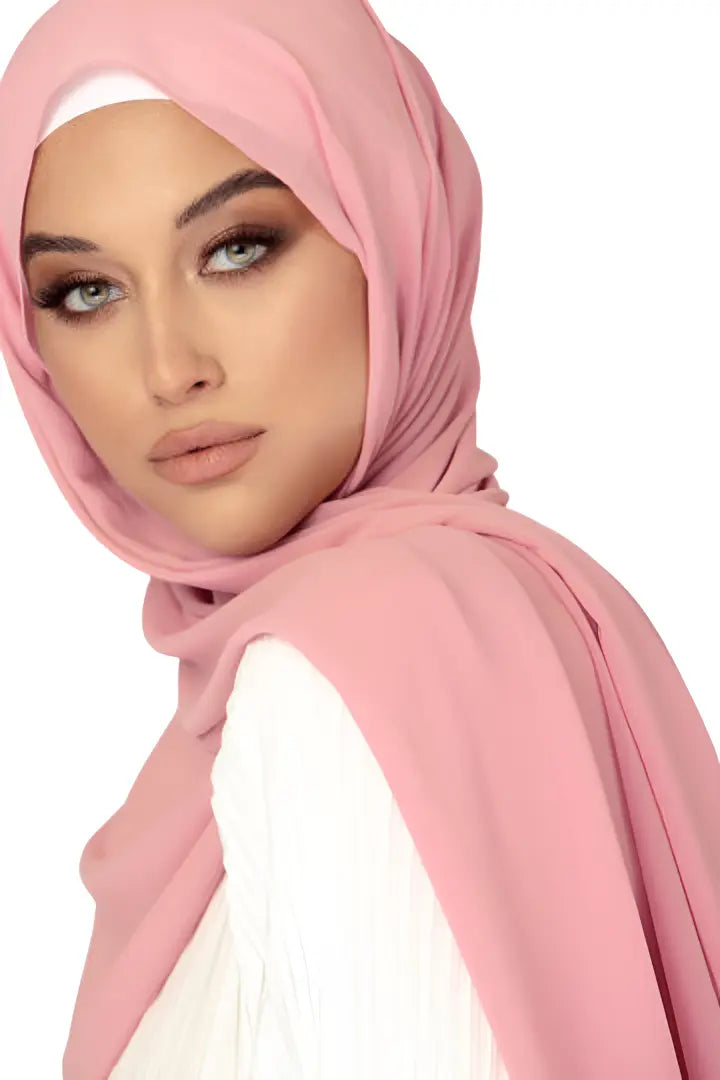Woman wearing a pink hijab against a white background