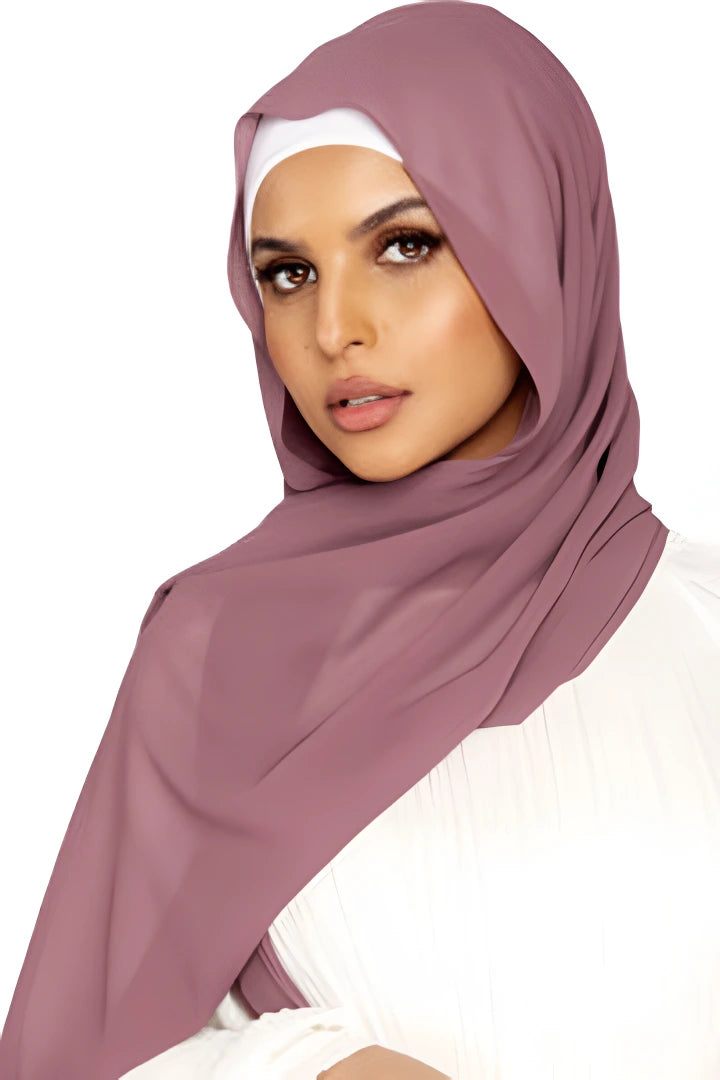 Woman wearing a mauve hijab and white top on a white background