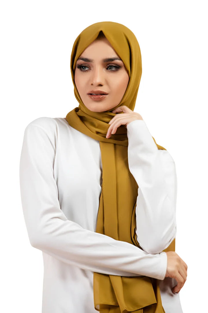 Woman wearing a mustard hijab and white top on a white background